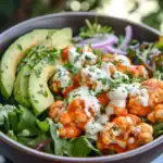 Creamy buffalo cauliflower bites with avocado slices, fresh greens, and herb dressing, perfect for vegan snacks or healthy appetizers. Delicious, spicy, and nutritious.