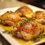 Juicy roasted chicken thighs topped with herbs, seasoned with spices, and cooked to perfection, served with fresh rosemary for a delicious Queen Recipes meal.